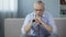 Sad male pensioner sitting on sofa, holding walking frame and looking down