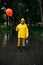 Sad man with balloon walking in park in rainy day