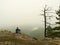 Sad man sit on the peak of sandstone rock and watching over the misty and foggy morning valley.