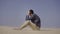 Sad man is sitting on a sand in desert. Sadness and depression concept