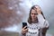 Sad middle age woman checking phone in autumn