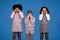 Sad offended international little girls in casual crying, isolated on blue background