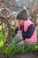 sad, offended, warmly dressed girl in a cap sits on her knees among the flowers of blue snowdrops in the vineyard