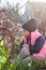 sad, offended, warmly dressed girl in a cap sits on her knees among the flowers of blue snowdrops in the vineyard