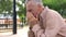 Sad old man sitting on hospital garden bench, pensioner crying in sorrow, loss