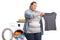 Sad overweight woman holding a shrunken shirt in front of a wash