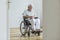 Sad paralyzed senior man in the wheelchair sitting alone at home