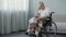 Sad pensioner sitting in wheelchair and waiting for his family at nursing home