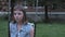 Sad pensive little caucasian girl swinging on swing at yard, looking at camera