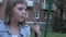 Sad pensive little caucasian girl swinging on swing at yard, looking at camera