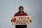 Sad plus size young african american woman in casual clothes looking at camera, holding End Racism banner in front of