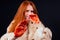 Sad redhaired ginger fashion victim woman with blood on her hands wearing natural fur coat and crying,studio black