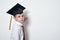 Sad schoolboy in academic hat writes on Board. Half-length portrait on white background copy space