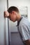 Sad schoolboy leaning head against wall in corridor