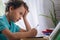 Sad schoolboy puts his hand under his head and looks at book