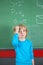 Sad Schoolboy Standing Against Board In Classroom