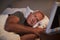 Sad Senior Man Lying In Bed Looking At Photo Frame