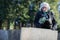 Sad Senior Woman With Flowers Standing By Grave