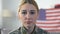 Sad servicewoman looking camera with american flag on background, memorial day