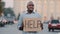 Sad stressed frustrated elderly african american poor man retirement age, lost tourist, holding cardboard banner with
