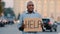 Sad stressed frustrated elderly african american poor man retirement age, lost tourist, holding cardboard banner with