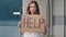 Sad stressed frustrated poor girl lost caucasian woman lady holding cardboard banner with inscription need help asks for