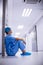 Sad surgeon sitting on floor in corridor