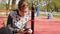 Sad teenage boy alone sitting on the Playground and using a smartphone. Outdoor. Concept of modern technologies and adolescent pro