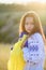 A sad teenage girl holds a Ukrainian flag to her chest