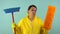 Sad and tired cleaning lady in a yellow suit on a blue background. The concept of professional house cleaning. The