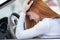 Sad tired yound woman driver sitting behind the car steering wheel in traffic jam