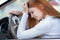 Sad tired yound woman driver sitting behind the car steering wheel in traffic jam