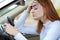 Sad tired yound woman driver sitting behind the car steering wheel in traffic jam