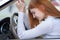 Sad tired yound woman driver sitting behind the car steering wheel in traffic jam