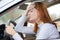 Sad tired yound woman driver sitting behind the car steering wheel in traffic jam