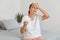 Sad unhappy young adult pregnant woman with pregnancy test posing in her bedroom, wearing white t shirt, looking away with sorrow