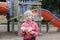 Sad upset Caucasian girl with baby toy on closed playground outdoor. Kids play area locked with yellow caution tape in Toronto,