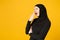 Sad upset tired confused young arabian muslim woman in hijab black clothes posing isolated on yellow wall background