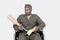 Sad US military officer in wheelchair holding prosthesis foot over gray background