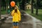 Sad woman with balloon walking in park, rainy day