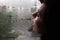 A sad woman blows air with her lips on a window fogged from rain
