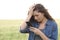 Sad woman checking phone in a wheat field