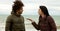 Sad woman confronting boyfriend in winter in front of ocean