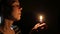 Sad woman deep in prayer with a candle in hands. Seeking help, despair in her eyes. 4K UHD.