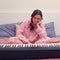 Sad woman experiences sitting at an electric piano on a home bed