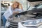 Sad woman looking into open car hood