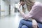 Sad woman in medical protective mask sitting in corridor of clinic