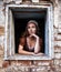 Sad woman in a rustic dress sitting near window in old house feel lonely. Cinderella style