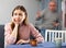 Sad woman sitting at table while her husband quarreling