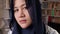 Sad young Asian muslim woman wearing hijab looking at camera, moody ambiance